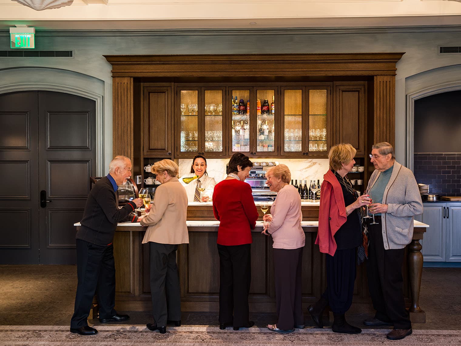 A group of residents enjoy glasses of wine at a bar.