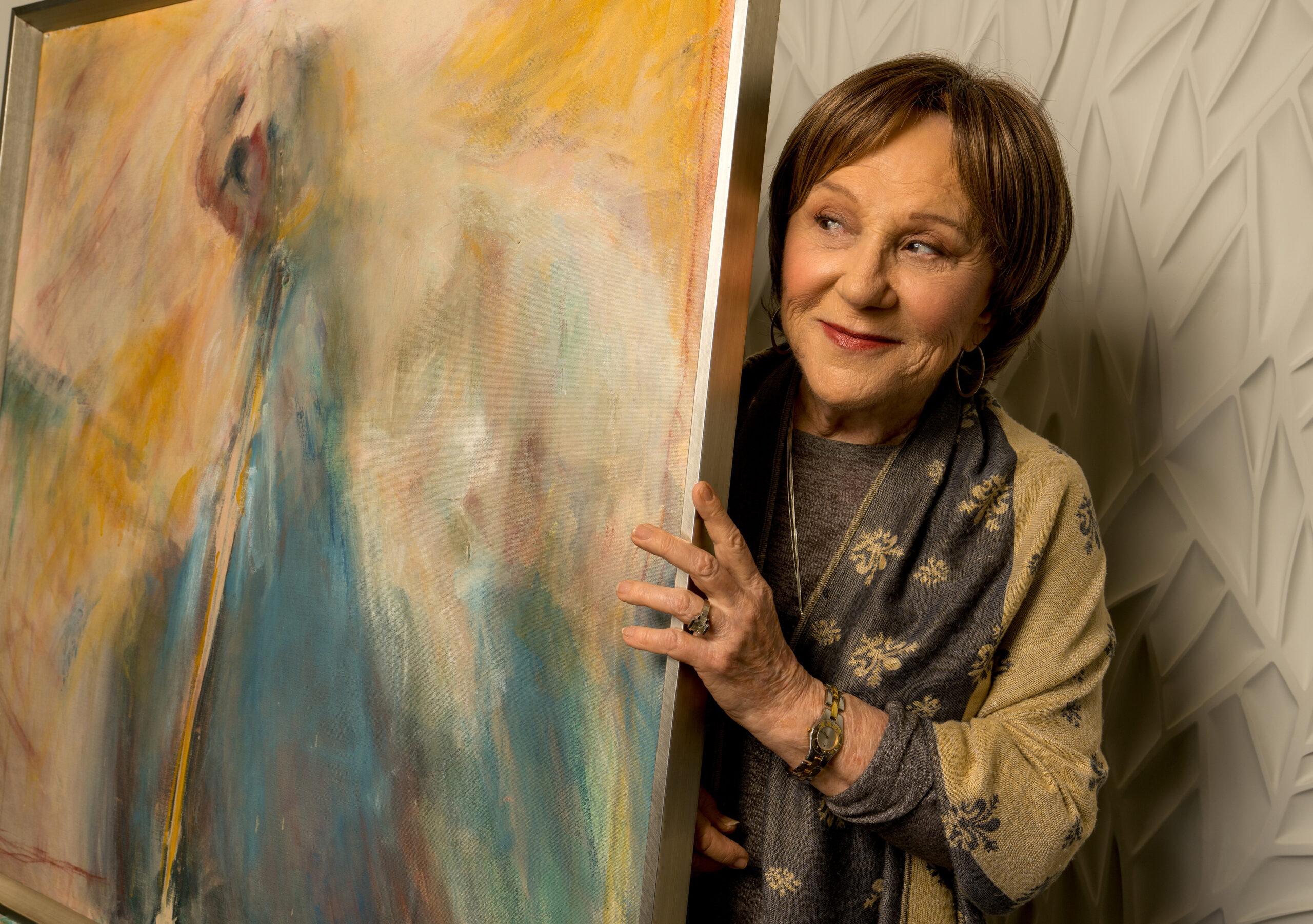 An artist holds an abstract painting.