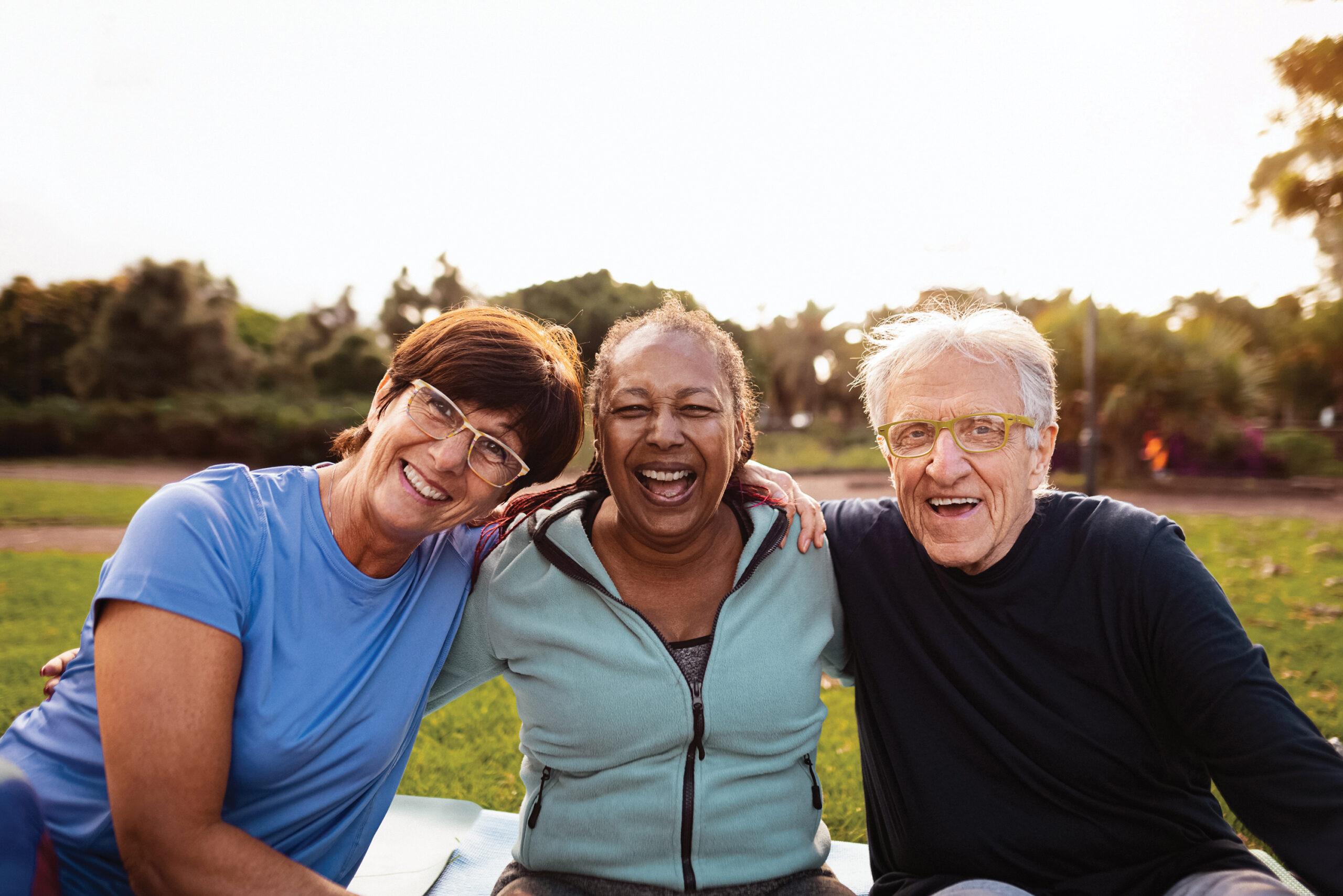 A group of three friends smiles outdoors.