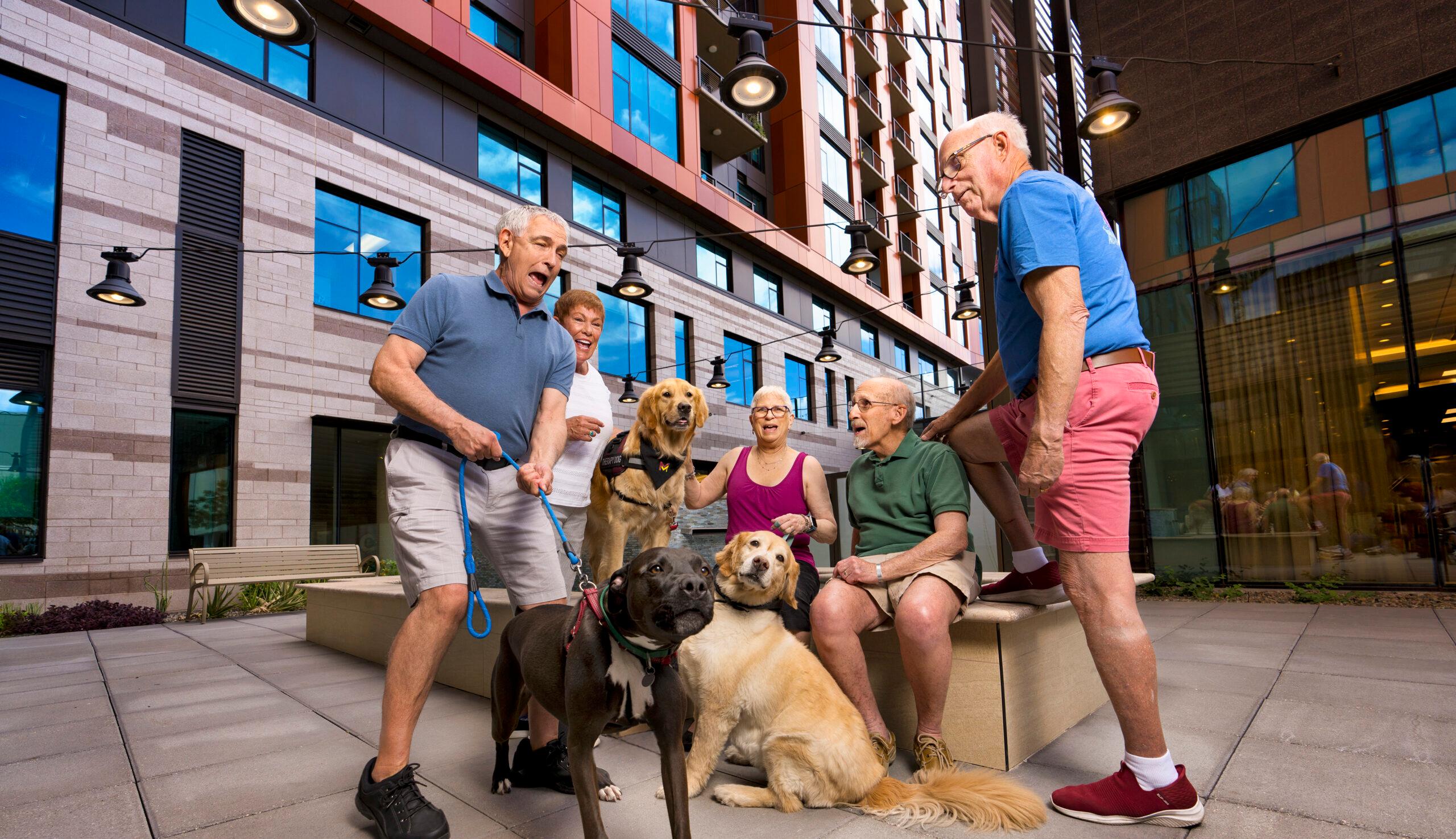 A group of cheerful residents and dogs outdoors.